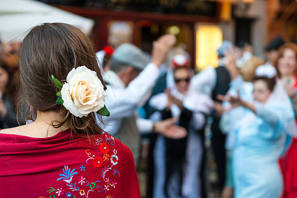 Madrid, Spain - May 15, 2015: A group of senior people dance on the streets of Madrid dressed in traditional costumes during the San Isidro religious festivals, under the watchful eye of a young woman with a flower in her head.