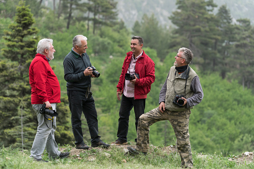 Group of landscape photographers discussing about photography in the forest.