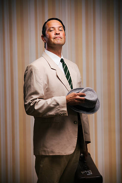 Studio shot of a man dressed in 1950´s style. He is carrying a suitcase and looking proudly at camera.