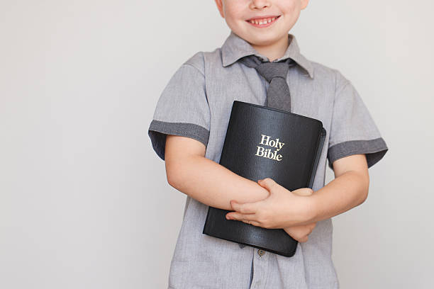 niño que sostiene el libro santo de la biblia - christ child fotografías e imágenes de stock