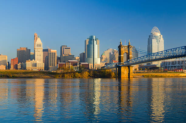 Cincinnati Skyline, Bridge, and River in the Morning Downtown Cincinnati skyline during the early morning, with the Ohio River and the Roebling Suspension Bridge in the foreground. ohio river photos stock pictures, royalty-free photos & images