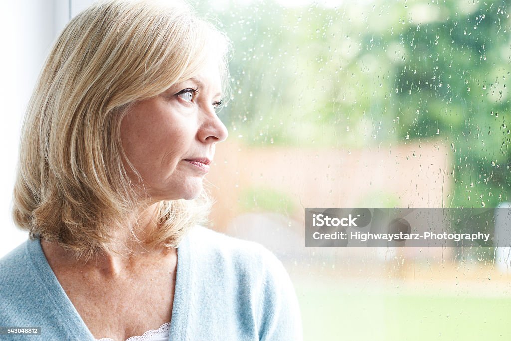 Sad Mature Woman Suffering From Agoraphobia Looking Out Of Windo Sad Mature Woman Suffering From Agoraphobia Looking Out Of Window Mature Women Stock Photo