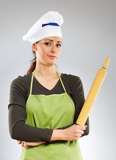 Lady chef with a rolling pin over gray background