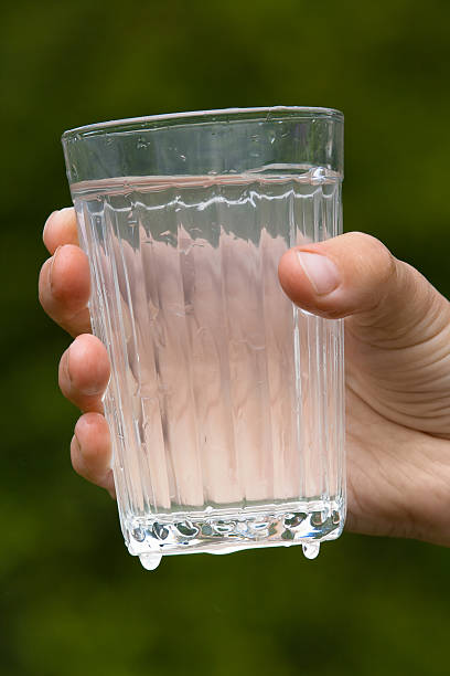 istock hand holding glass with water on blurred background 543051174