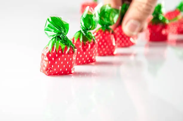 Photo of hand taking strawberry shaped candies