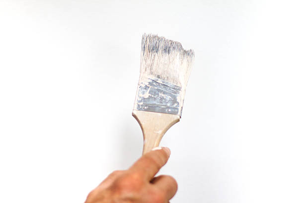 istock Man's Hand Painting White Wall with Brush 543058050