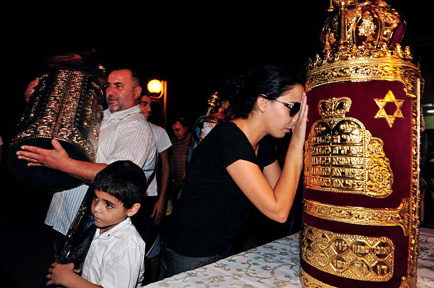 Celebrating Jewish Holiday Simchat Torah in a Synagogue Sderot, Israel - September 30, 2010: Israeli men and women celebrate Simchat Torah by dancing with the scrolls of the Torah at a Synagogue in Sderot, Israel. Simchat Torah is a celebratory Jewish holiday that marks the completion of the annual Torah reading cycle. simchat torah photos stock pictures, royalty-free photos & images