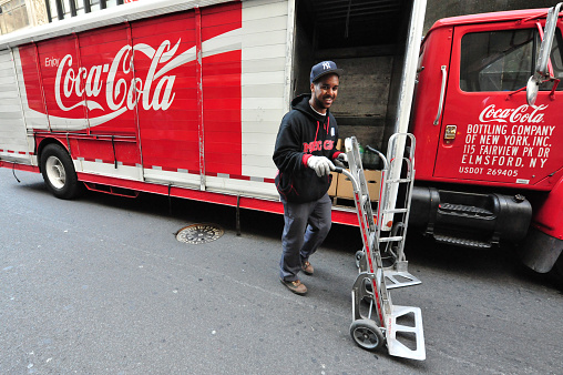 New York, New York, United States - October 14, 2009: Man delivers coke from a Coca Cola truck in Manhattan New York. The red and white Coca-Cola logo is recognized by 94% of the world's population