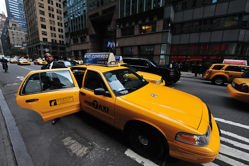 New York, New York, United States - October 14, 2009: Afro American businessman exit a yellow taxicab in Manhattan New York. Over a million people ride a cab every day