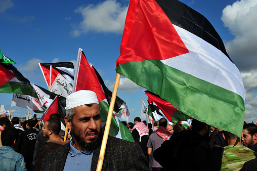 Erez Crossing, Israel - December 31, 2009: A large group of Palestinian Arabs carry Palestinian flags during a protest on the Gaza-Israel border. The entire  Palestinian population in Gaza Strip is 1. 6 million people.