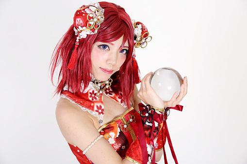 Young asian girl dressed in cosplay costume with crystal ball on white background