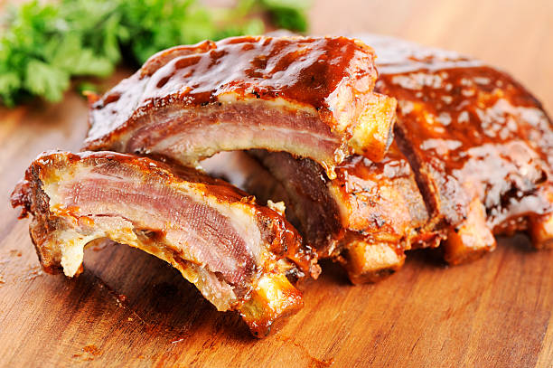 Grilled barbecue ribs Grilled sliced barbecue pork ribs on a wooden cutting board, selective focus. barbecue pork stock pictures, royalty-free photos & images