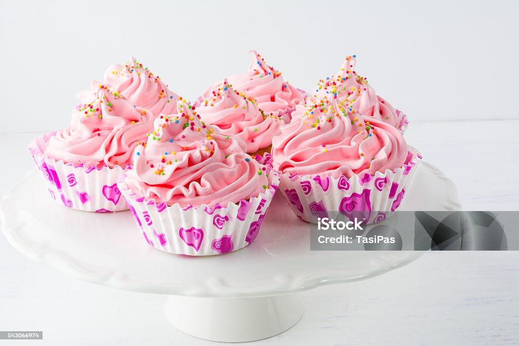 Decorated pink birthday cupcakes  on the cake stand Decorated pink birthday cupcakes  on the cake stand. Sweet dessert  pastry with whipped cream. Birthday homemade cupcakes served for party. Baked Stock Photo