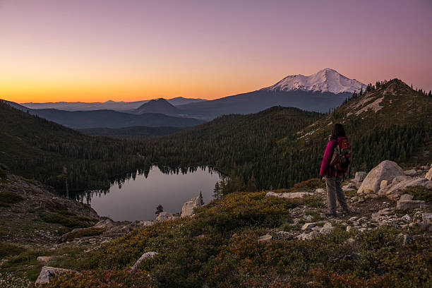 Hiker watching sunset on the mountain. Female hiker on the slopes of a mountain watching sunset with Mt. Shasta in the background. mt shasta photos stock pictures, royalty-free photos & images