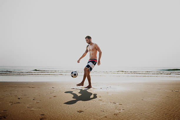 hombre guapo jugando fútbol beach concepto - beach football fotografías e imágenes de stock