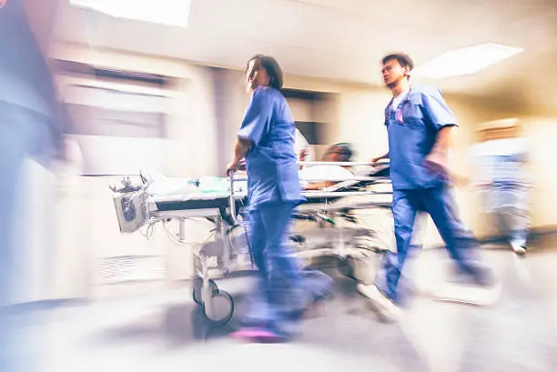 Doctors and nurses pulling hospital trolley,