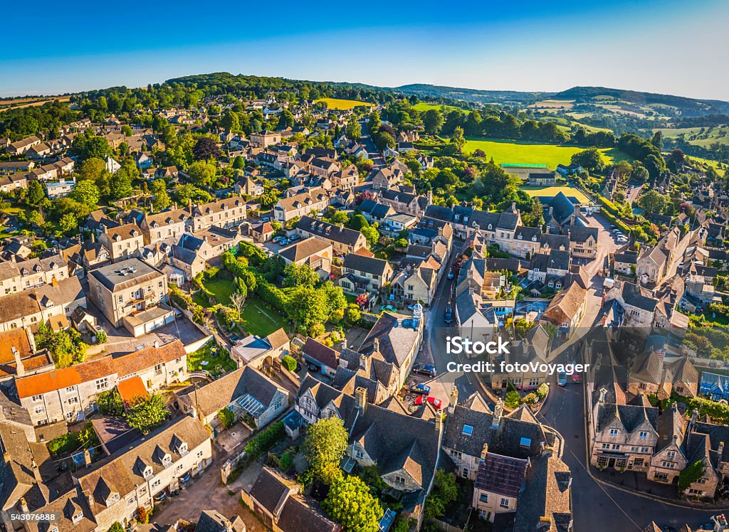 Aerial view over pretty rural village cottages summer fields Cotswolds Aerial view over the iconic Cotswold village of Painswick, with its honey coloured limestone cottages deep in the bucolic countryside of Gloucestershire, UK, framed by vibrant green patchwork fields and clear blue summer skies. ProPhoto RGB profile for maximum color fidelity and gamut. UK Stock Photo