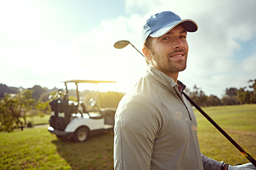 Portrait of a young man holding a golf club while enjoying a day on the golf course