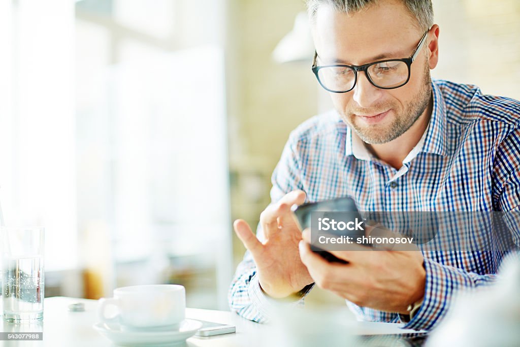 Writing sms Mature businessman writing sms in office Mobile Phone Stock Photo