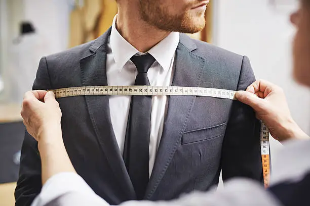Tailor measuring front of businessman jacket