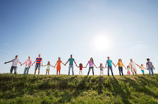 Large group of happy people holding hands against the sky.