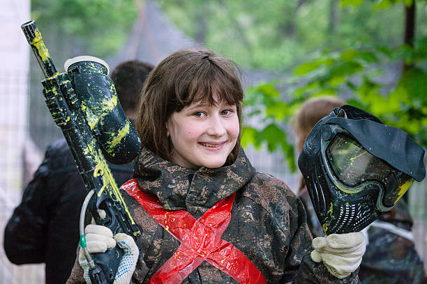 girl in camouflage after paintball game smiling girl in camouflage with a gun after playing paintball face guard sport photos stock pictures, royalty-free photos & images