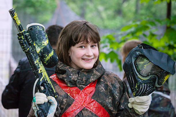 girl in camouflage after paintball game smiling girl in camouflage with a gun after playing paintball paintballing stock pictures, royalty-free photos & images