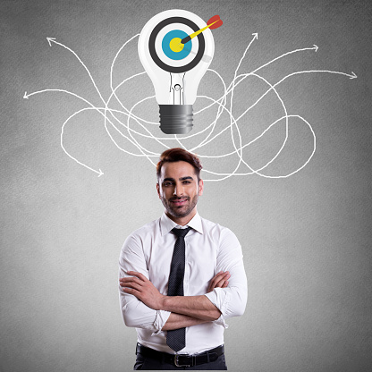 Young businessman looking at bull's eye on light bulb