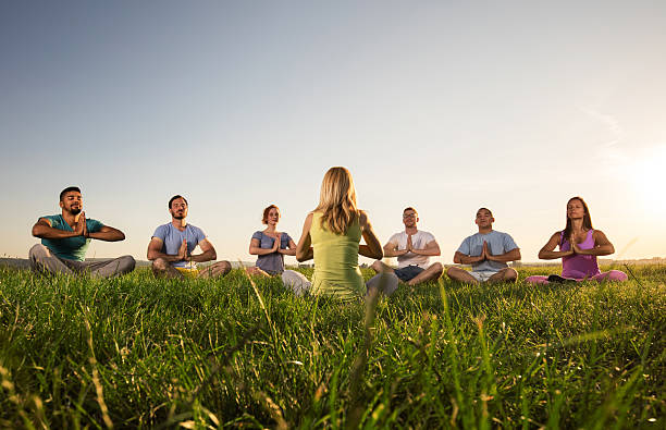 gruppo di persone meditazione durante la lezione di yoga al tramonto. - sunset yoga young men caucasian foto e immagini stock