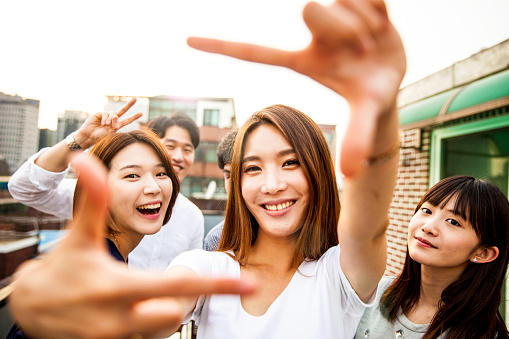 Friends having fun and greetings together starting a rooftop party in Seoul - Hondae district.