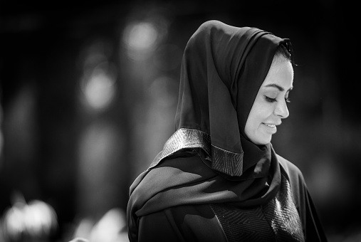 A young Emirati woman looking down, wearing traditional dress.