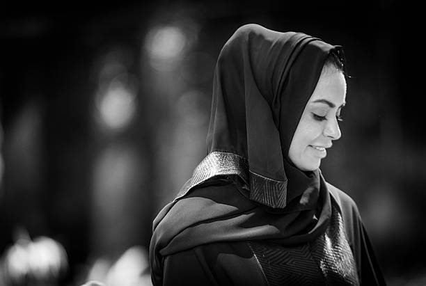 Arab Woman A young Emirati woman looking down, wearing traditional dress. hijab photos stock pictures, royalty-free photos & images