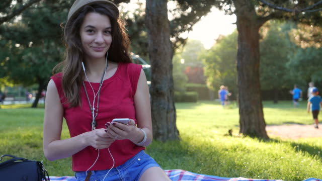 Young pretty girl listening to music in the park