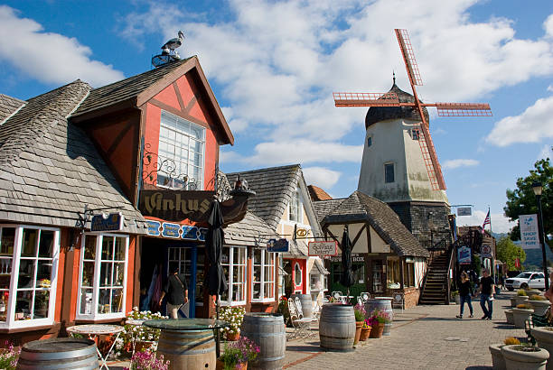 Solvang - danish city in California Solvang, USA - May 10, 2016: Street of Solvang, California, in May 2016, with people on the boardwalk, cafes, shops and a windmill in the back danish culture photos stock pictures, royalty-free photos & images
