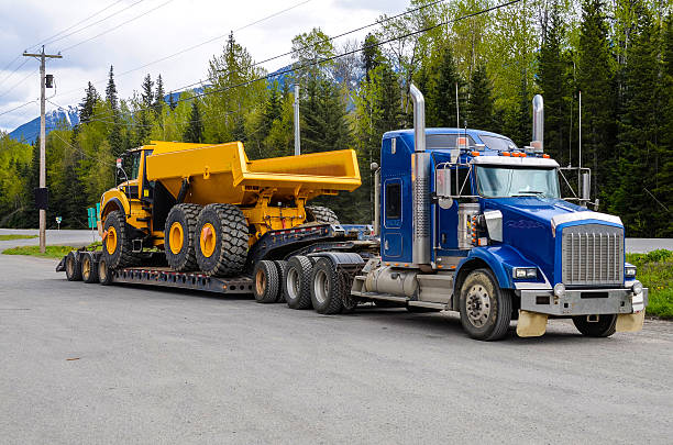 Heavy hauling Big truck with a low platform trailer carrying a tipper truck on a public parking area of a truck stop heavy haulage stock pictures, royalty-free photos & images