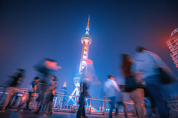 woman traveler visiting in Shanghai, China. Female Tourist with backpack sightseeing Shanghai view of Lujiazui in The Bund of Shanghai at night. landmark and popular for tourism attractions