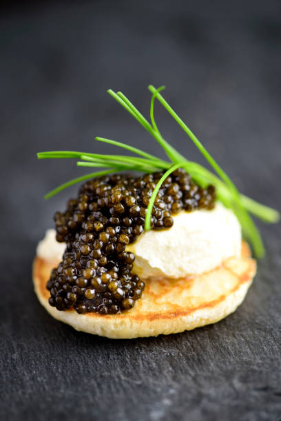 Blini with Sour Cream and Real Black Caviar Blini with Sour Cream and Real Black Caviar Close-up caviar stock pictures, royalty-free photos & images