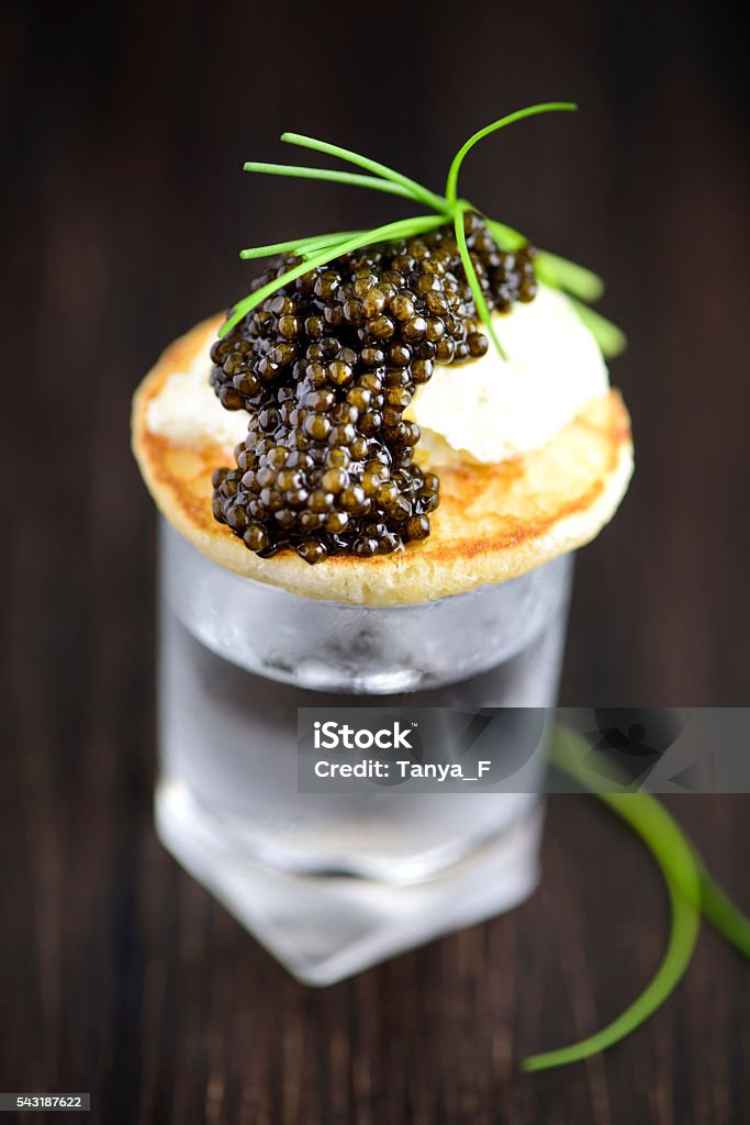 Blini and Real Black Caviar Appetizre with Vodka Mini Blini with Sour Cream and Real Black Caviar, Served on a Vodka Glass Caviar Stock Photo
