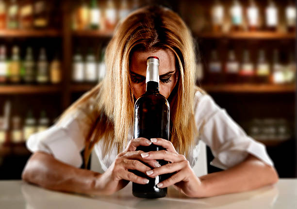 drunk alcoholic woman alone depressed with wine bottle in bar - stereotypical housewife depression sadness women imagens e fotografias de stock