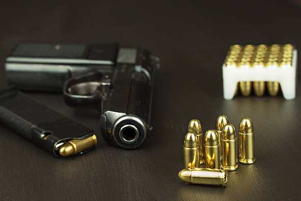 istock Handgun with ammunition on a dark wooden table 543192008