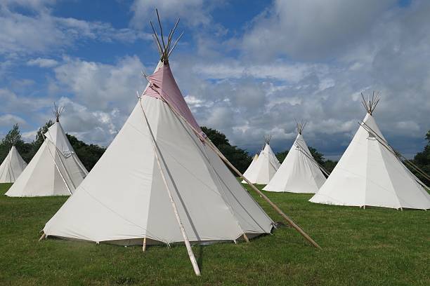 Glamping camping tipis tepees in a field on a sunny day stock photo