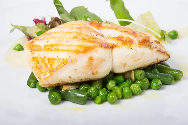 Fried white fish fillet with peas garnish