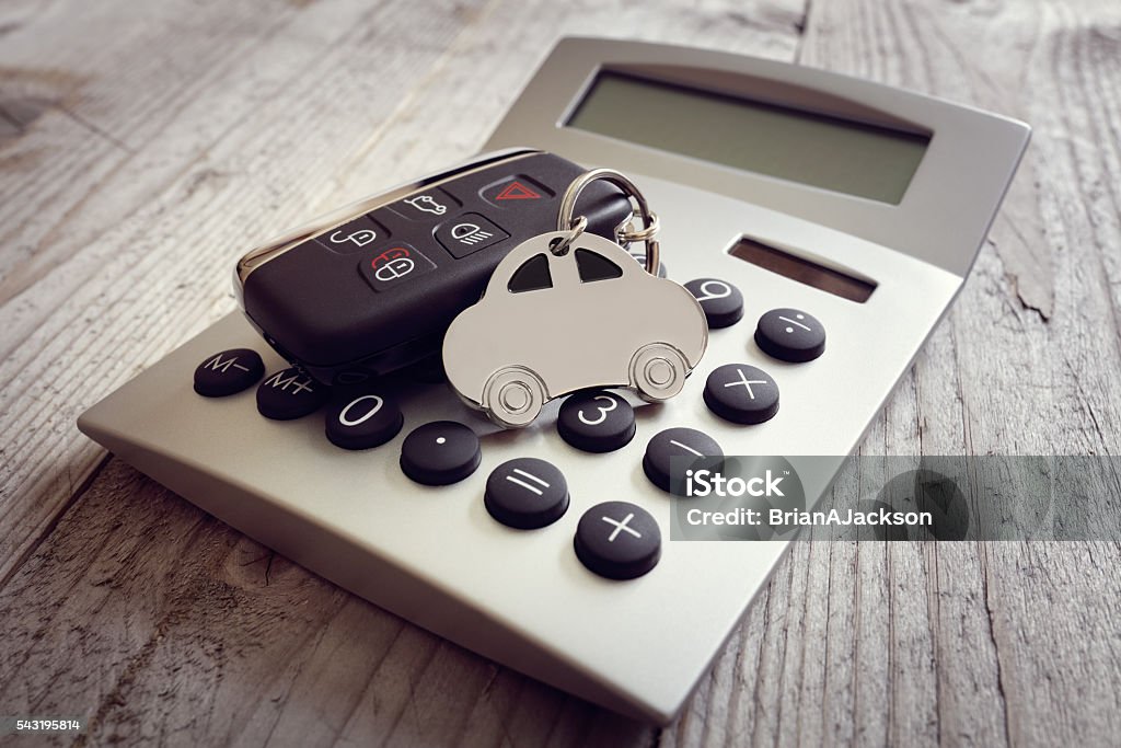 Car shape keyring and key on calculator Car shape keyring and key on calculator concept for motoring costs, finance, insurance, servicing or fuel bills Car Stock Photo