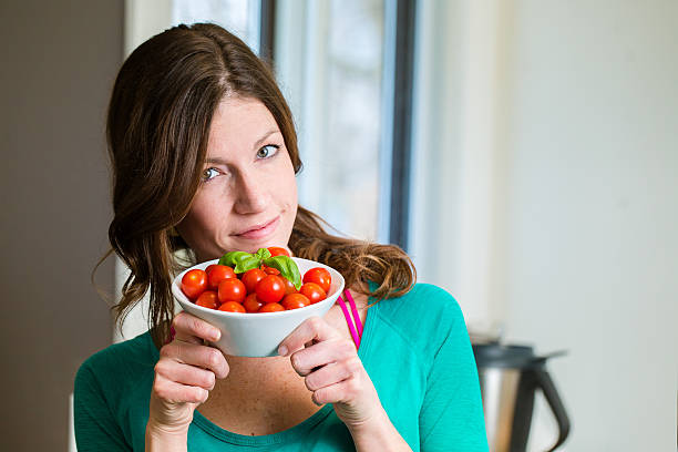 Young woman showing a cherry tomatoes bowl