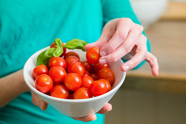 Young woman showing a cherry tomatoes