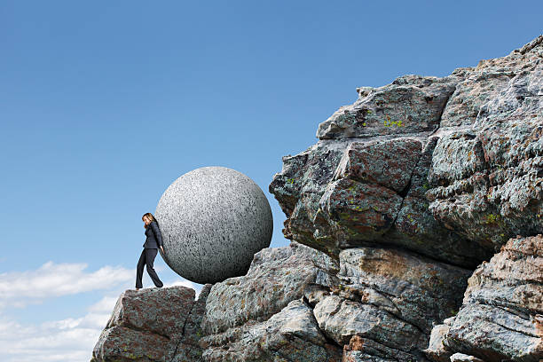 istock Businesswoman Pushing Sphere Up Rocky Cliff 543202832