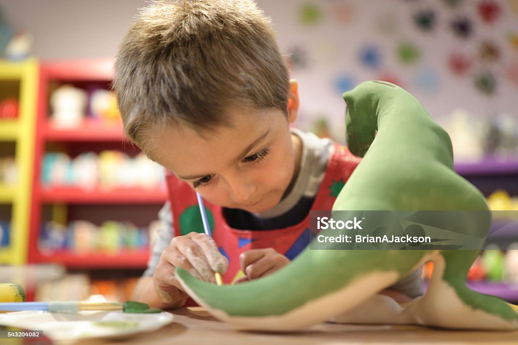 Creative education Child painting a ceramic pottery model dinosaur at school concept for art and creative education Child Stock Photo