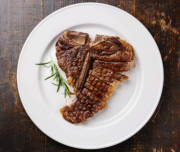 Sliced T-Bone Steak on plate Sliced grilled T-Bone Steak on white plate on wooden background t bone steak stock pictures, royalty-free photos & images