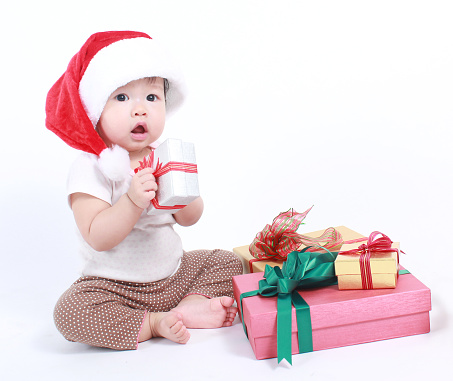 Little baby celebrates Christmas. New Year's holidays. Baby in a Christmas costume with gift