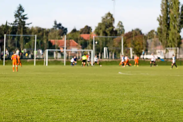 Shallow depth of field shot of group of male soccer players playing amateur soccer match on sunny summer day on simple sports venue in Denmark.